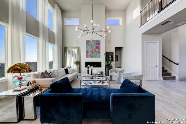 living room featuring a towering ceiling, light hardwood / wood-style flooring, and a chandelier