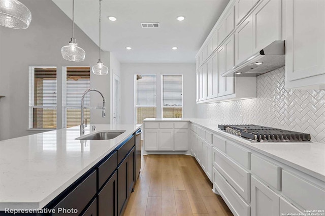 kitchen with sink, white cabinetry, hanging light fixtures, stainless steel appliances, and a center island with sink