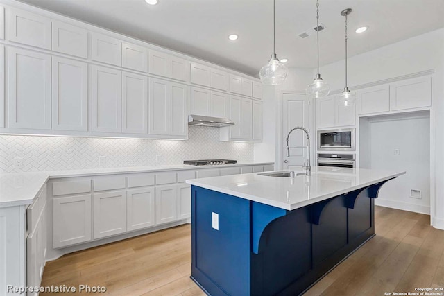 kitchen featuring stainless steel appliances, white cabinetry, a kitchen island with sink, and sink