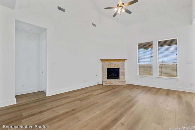 unfurnished living room featuring ceiling fan, light wood-type flooring, a fireplace, and high vaulted ceiling