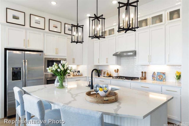 kitchen featuring white cabinetry, a kitchen island with sink, hanging light fixtures, and stainless steel appliances