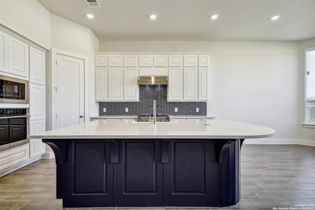 kitchen with tasteful backsplash, stainless steel appliances, ventilation hood, a breakfast bar area, and a large island