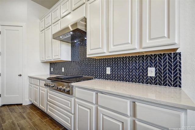 kitchen featuring white cabinets, light stone counters, stainless steel gas cooktop, and wall chimney range hood