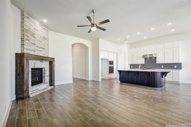 kitchen featuring hardwood / wood-style flooring, a kitchen bar, white cabinetry, and an island with sink