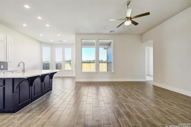 kitchen with hardwood / wood-style flooring, a breakfast bar, ceiling fan, and white cabinetry