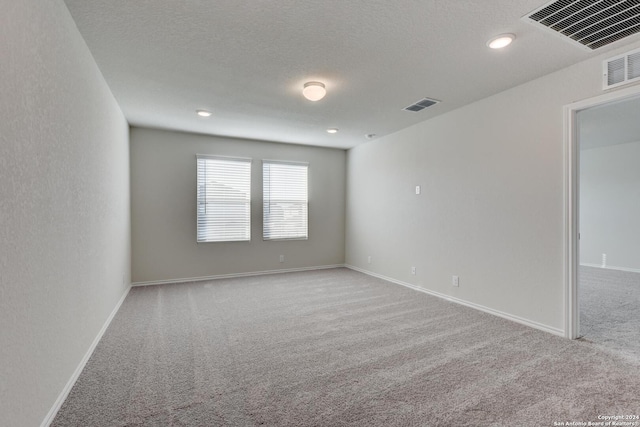 empty room with light carpet and a textured ceiling