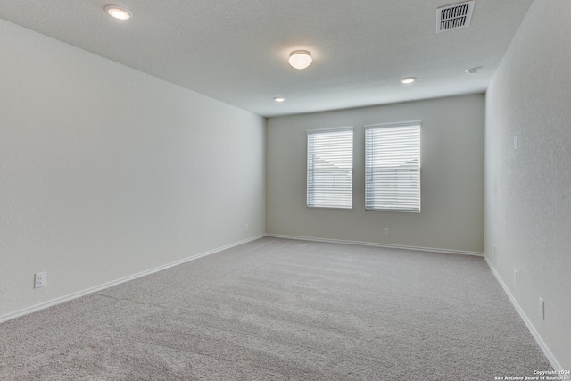 unfurnished room featuring a textured ceiling and light carpet