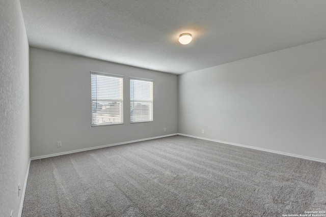 carpeted empty room featuring a textured ceiling