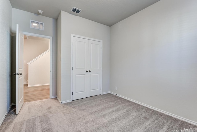 unfurnished bedroom with light colored carpet and a closet