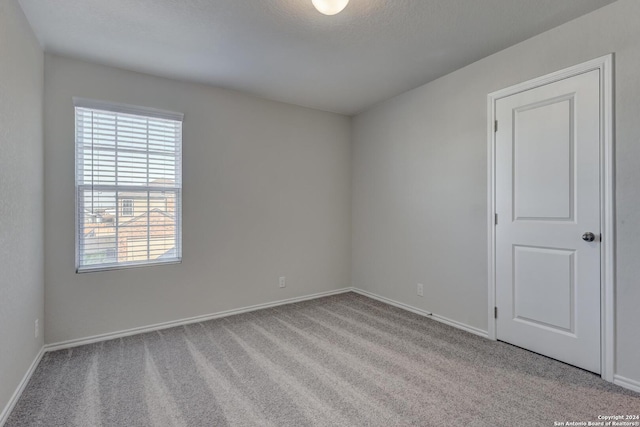 carpeted empty room with a textured ceiling