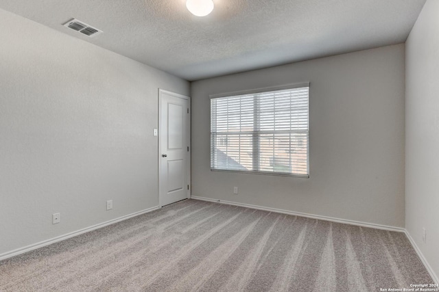 carpeted spare room featuring a textured ceiling