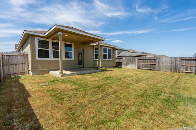 back of property with a yard and a patio