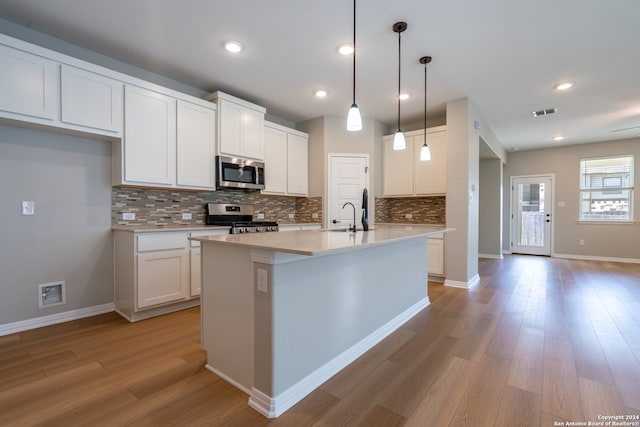 kitchen with appliances with stainless steel finishes, light wood-type flooring, decorative light fixtures, and white cabinetry