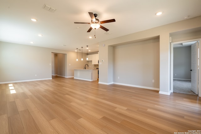 unfurnished living room featuring ceiling fan, sink, and light hardwood / wood-style floors