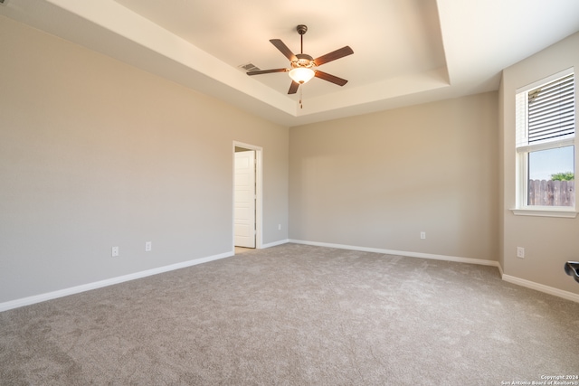 carpeted spare room with ceiling fan and a raised ceiling