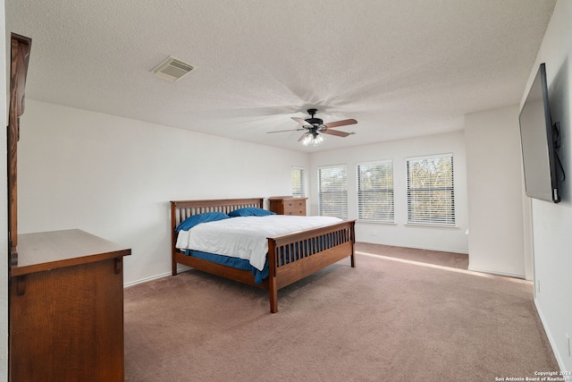 carpeted bedroom featuring ceiling fan and a textured ceiling