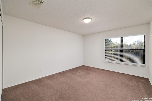 spare room featuring dark colored carpet and a textured ceiling