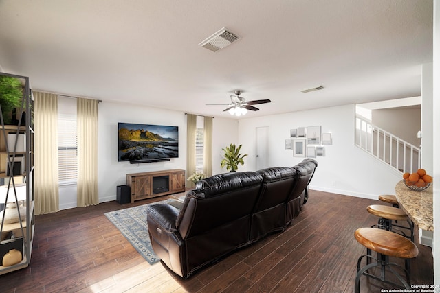 living room featuring ceiling fan and dark wood-type flooring