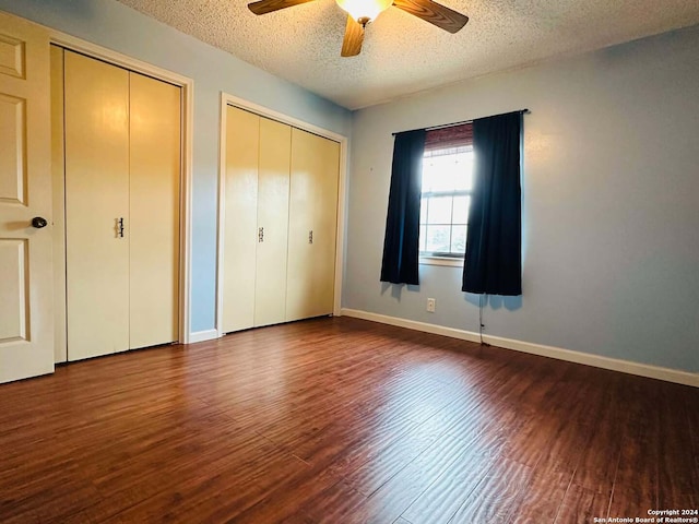 15618 Elks Pass St, San Antonio, TX 78232 - unfurnished bedroom featuring multiple closets, dark wood-style flooring, a textured ceiling, baseboards, and a ceiling fan