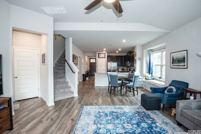 living room featuring ceiling fan, light hardwood / wood-style floors, and lofted ceiling