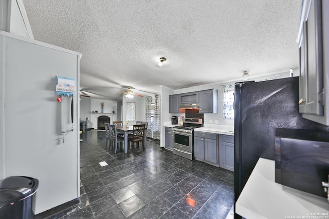 kitchen featuring black fridge, stainless steel gas range, ceiling fan, gray cabinets, and a textured ceiling