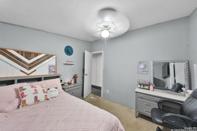 bedroom featuring a textured ceiling, light colored carpet, and ceiling fan