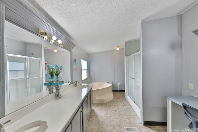 bathroom with a textured ceiling, vanity, and separate shower and tub