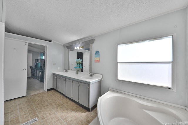 bathroom featuring a bathing tub, a textured ceiling, and a healthy amount of sunlight