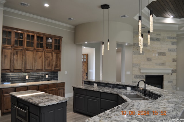 kitchen with light stone countertops, a center island, dark brown cabinetry, and sink