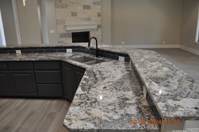 kitchen featuring a fireplace, light stone counters, sink, and light hardwood / wood-style flooring