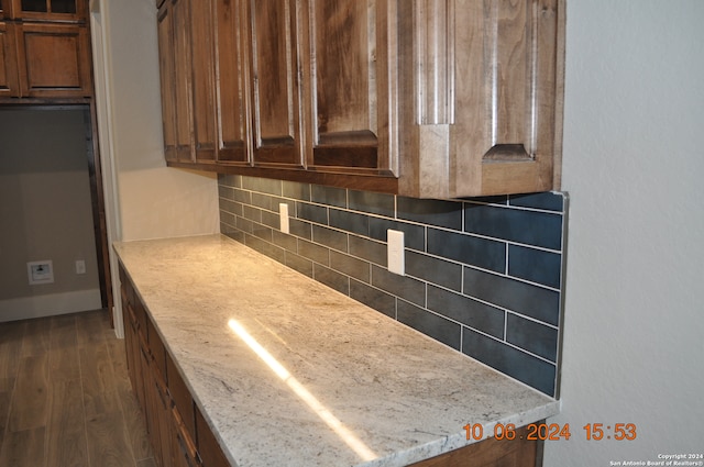 kitchen with backsplash, light stone counters, and dark hardwood / wood-style floors