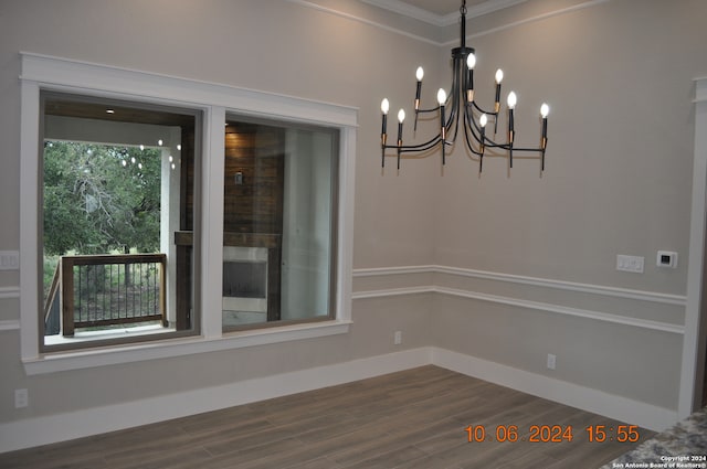 unfurnished room featuring dark hardwood / wood-style floors, ornamental molding, and an inviting chandelier