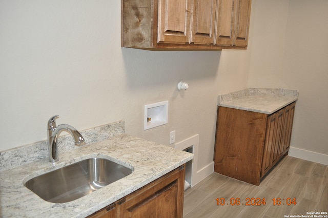 clothes washing area with hookup for a washing machine, sink, cabinets, and light hardwood / wood-style floors