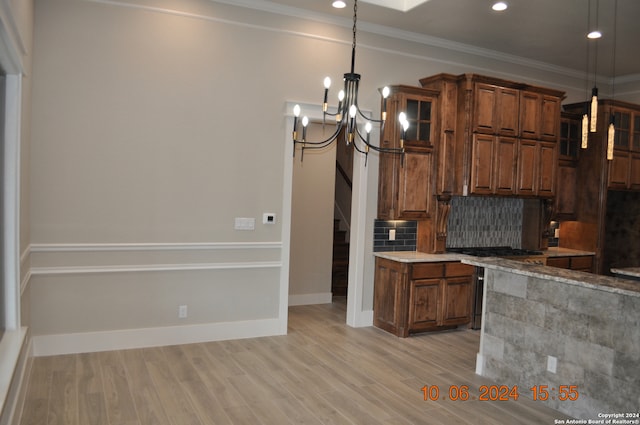 kitchen featuring tasteful backsplash, a chandelier, light hardwood / wood-style floors, decorative light fixtures, and ornamental molding