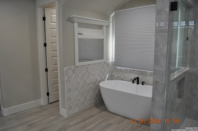 bathroom with a tub, wood-type flooring, and tile walls