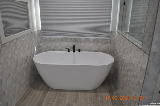 bathroom with a bathtub, tile walls, and hardwood / wood-style flooring