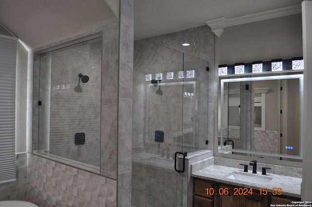 bathroom with vanity, a shower with shower door, and ornamental molding