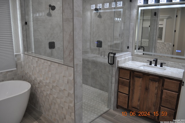 bathroom featuring vanity, tile walls, and plus walk in shower