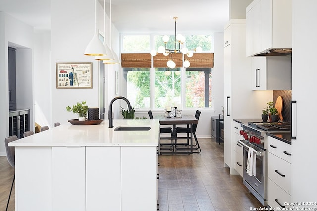 kitchen with a notable chandelier, a kitchen island with sink, sink, and high end stainless steel range