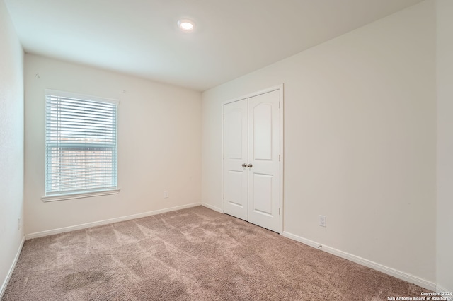 unfurnished bedroom with light carpet and a closet