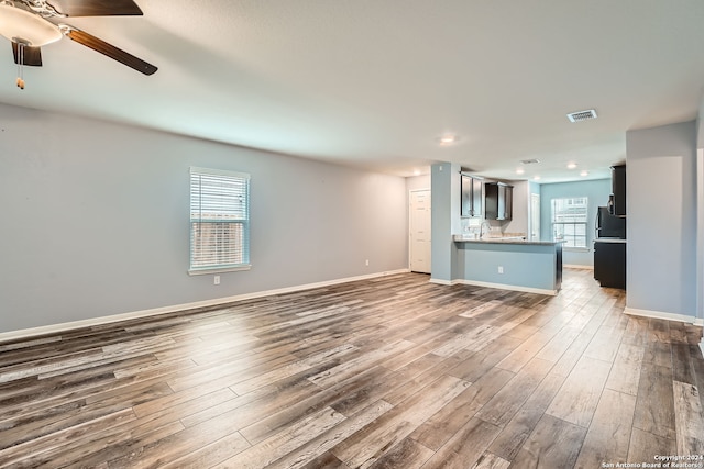 unfurnished living room with dark hardwood / wood-style flooring, ceiling fan, plenty of natural light, and sink