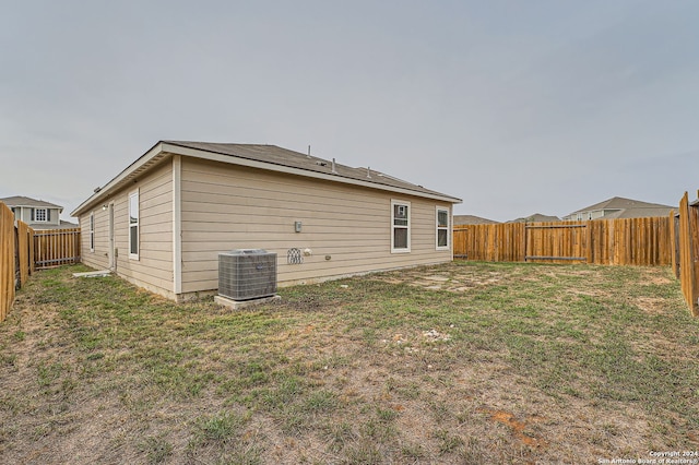 back of property featuring a lawn and cooling unit