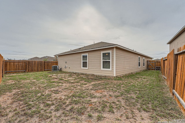 rear view of house with cooling unit and a yard