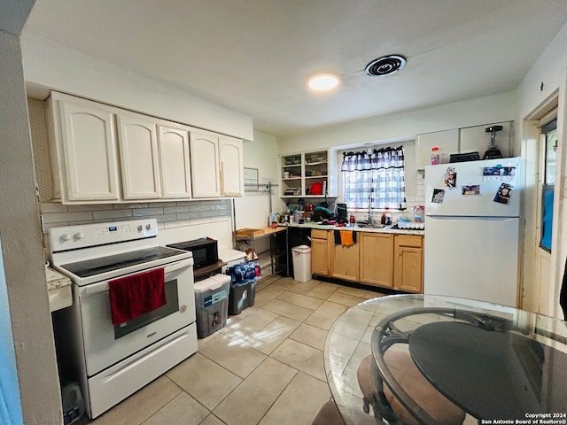 kitchen featuring tasteful backsplash, white appliances, sink, light tile patterned floors, and white cabinets