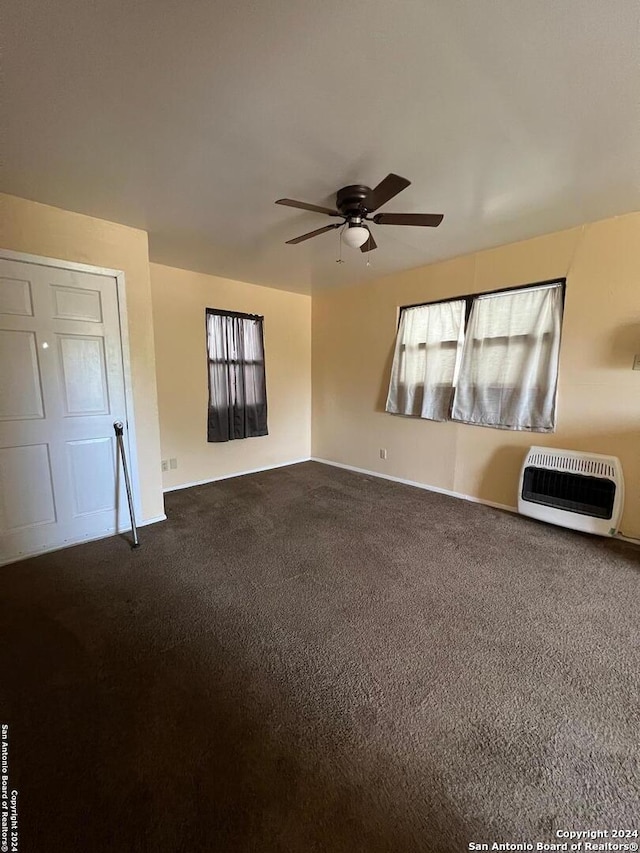 carpeted spare room featuring heating unit and ceiling fan