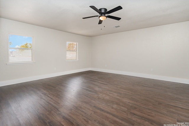 unfurnished room featuring plenty of natural light, ceiling fan, and dark wood-type flooring