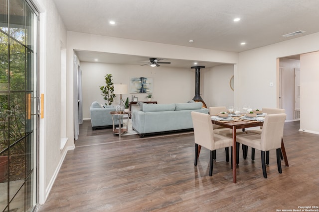 dining room with dark hardwood / wood-style floors, a wood stove, and ceiling fan