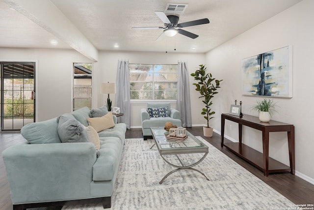 living room featuring dark hardwood / wood-style floors, ceiling fan, and a textured ceiling