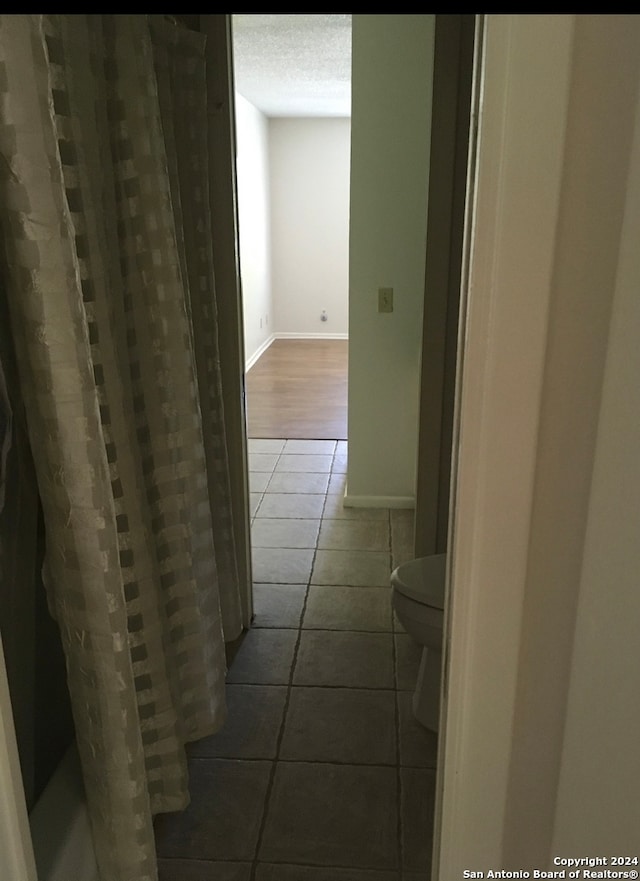 hall featuring dark tile patterned floors and a textured ceiling