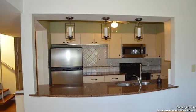 kitchen with kitchen peninsula, appliances with stainless steel finishes, decorative backsplash, decorative light fixtures, and dark stone countertops